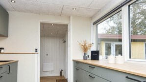 A modern kitchen with grey cabinets, a wooden countertop, and a window with a view of trees. - 8 Person Holiday Home in Skjern (Skjern)