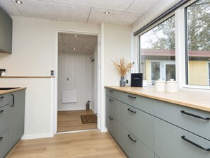 A modern kitchen with grey cabinets, a wooden countertop, and a window with a view of trees. - 8 Person Holiday Home in Skjern (Skjern)