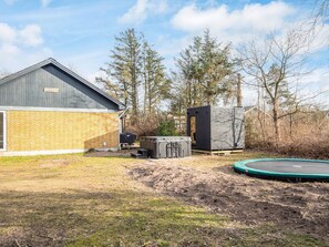 A backyard with a hot tub, a covered grill, and a trampoline. - 8 Person Holiday Home in Skjern (Skjern)