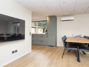 A modern kitchen with grey cabinets and a wooden dining table with black chairs. - 8 Person Holiday Home in Skjern (Skjern)