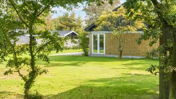 A residential area with a grassy lawn, a wooden fence, and a brick building with a glass door.
