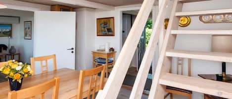 A wooden dining table with chairs, a vase of flowers, and a staircase leading to an upper level.