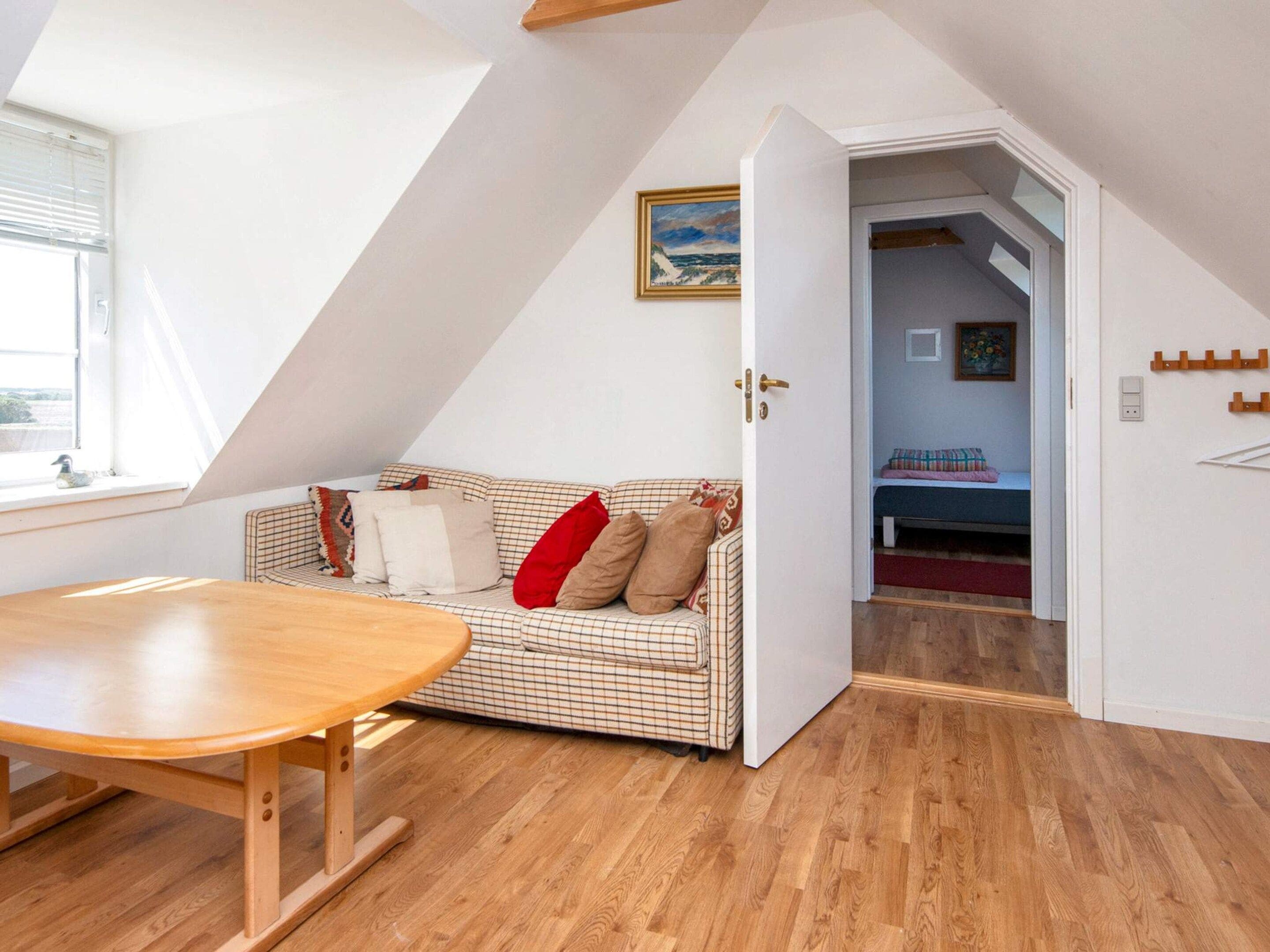 Una habitación con un sofá a cuadros, una mesa de madera y un cuadro en la pared.