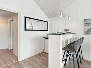 A modern kitchen with a bar area, wooden flooring, and pendant lighting. - 5 Star Holiday Home in Sydals (Sydals)