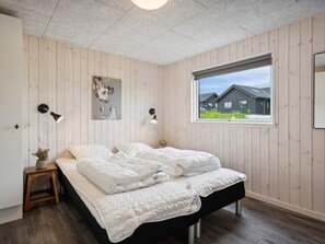 A bedroom with a bed, a window with a view, a wall-mounted lamp, and a small table with a plant. - 5 Star Holiday Home in Sydals (Sydals)