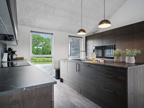 Una cocina moderna con armarios de madera oscura, encimera negra e iluminación colgante.