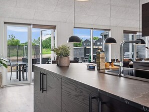 A modern kitchen with a large island, built-in appliances, and large windows offering a view of the outdoors.