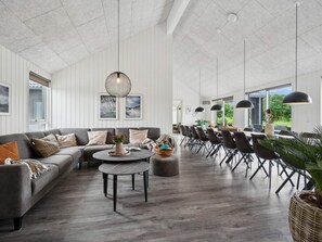 A spacious living area with a grey sofa, a round coffee table, and a dining area with a long table and chairs. - 5 Star Holiday Home in Sydals (Sydals)