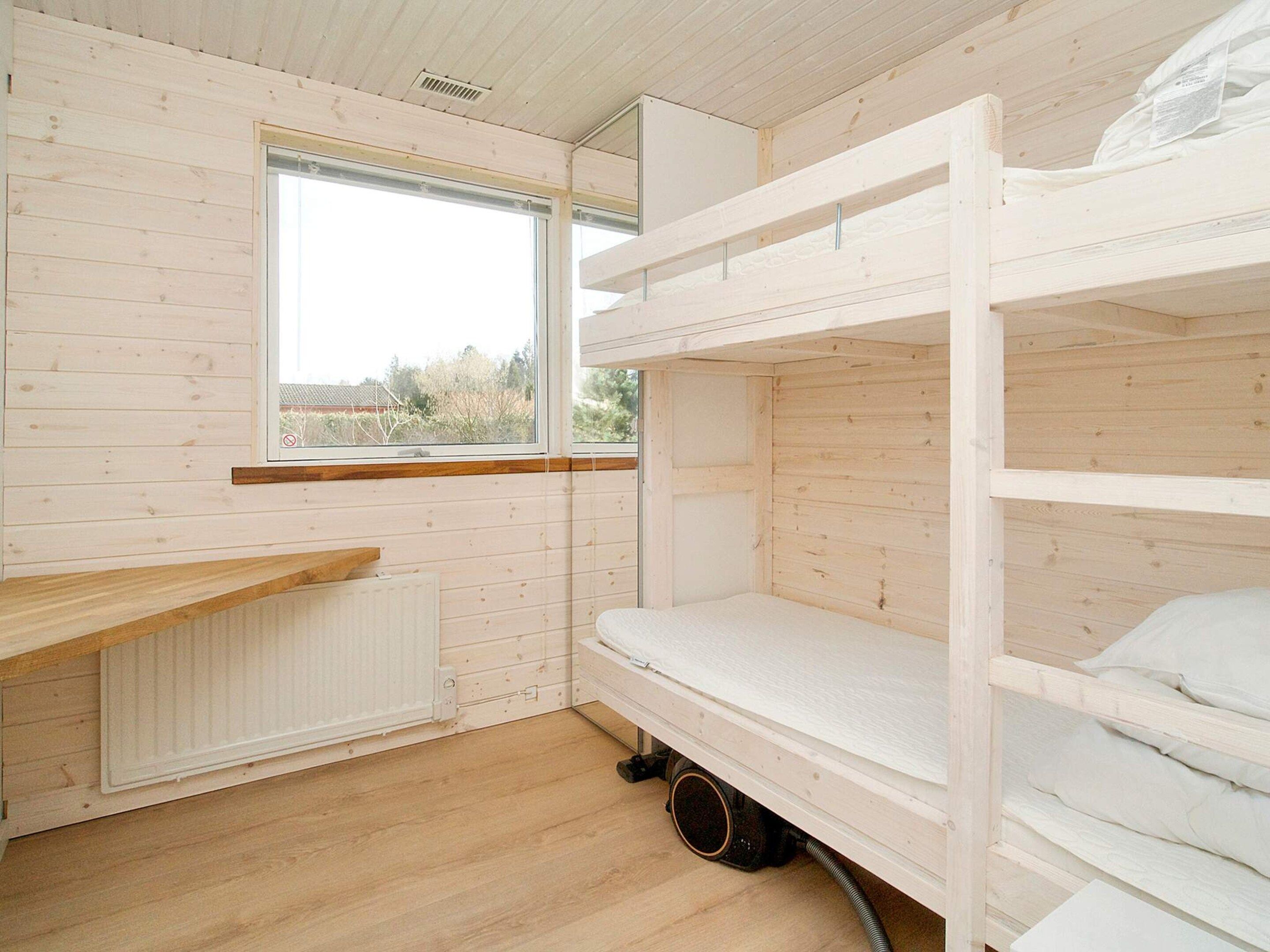 Habitación con literas, ventana, paredes de madera y radiador.