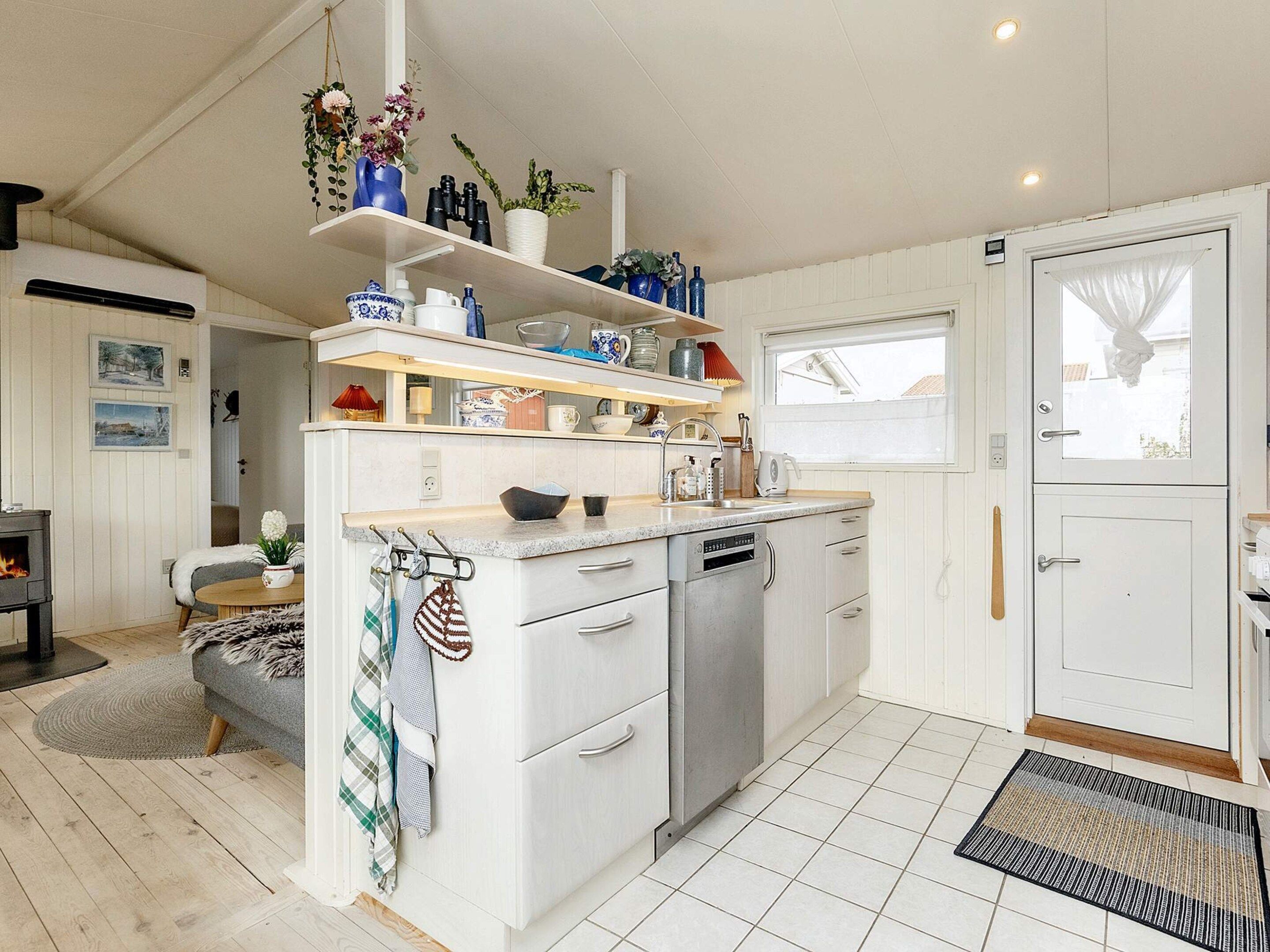 A modern kitchen with white cabinetry, a dishwasher, and a countertop with various kitchen items.