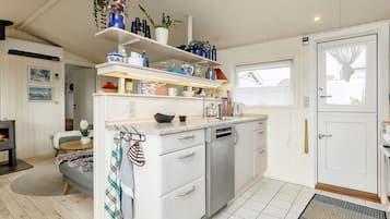 A modern kitchen with white cabinetry, a dishwasher, and a countertop with various kitchen items.