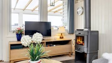 Ein gemütliches Wohnzimmer mit Fernseher, Kamin und einem runden Tisch mit Blumen in einer Vase.