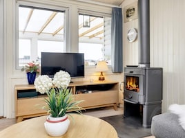 Una sala de estar acogedora con televisor, chimenea y una mesa redonda con un jarrón de flores.