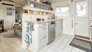 A modern kitchen with white cabinetry, a dishwasher, and a countertop with various kitchen items. - 5 Person Holiday Home in Karrebaeksminde (Karrebæksminde)