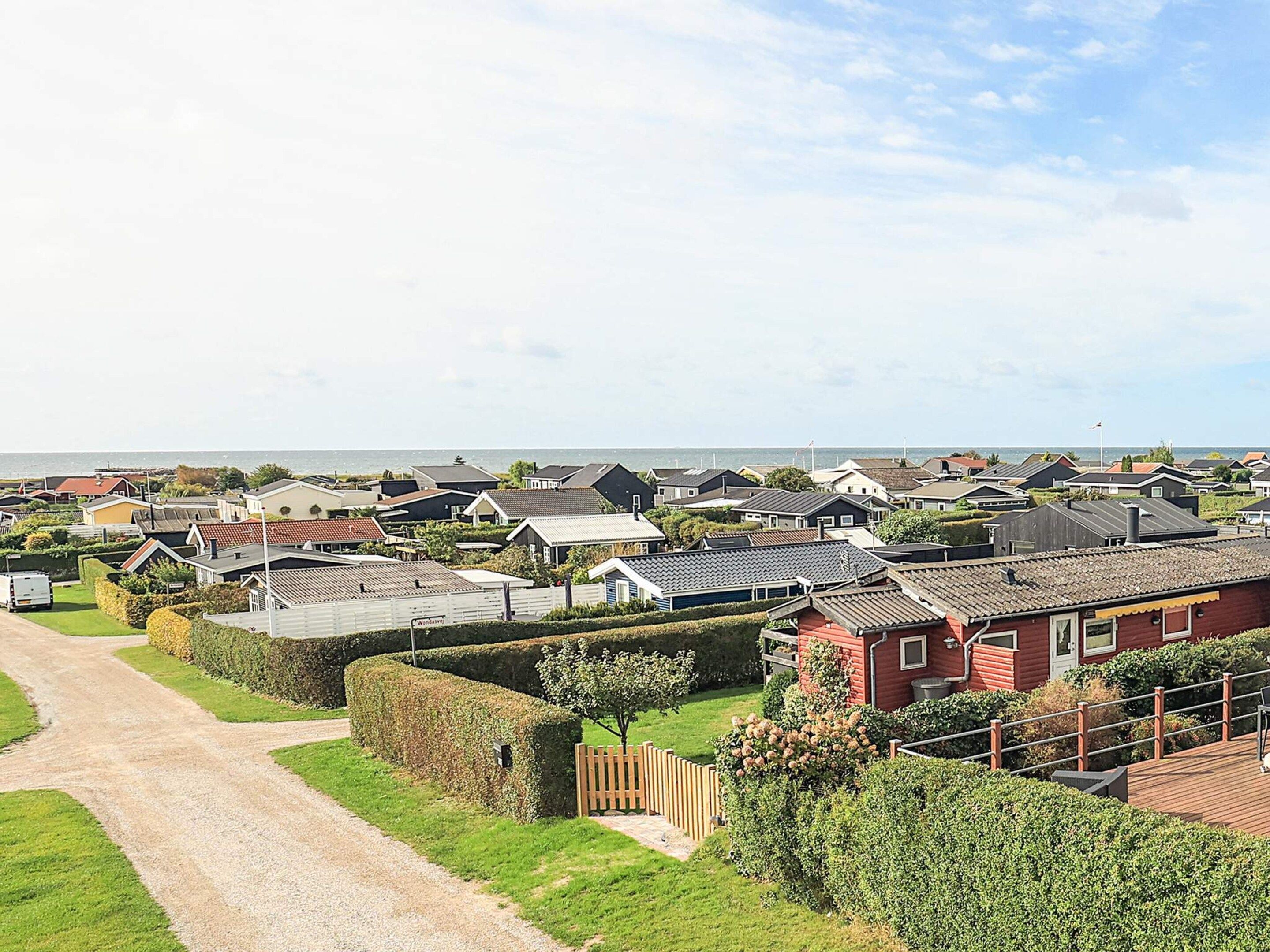 A coastal residential area with houses, a gravel path, and a view of the sea.
