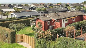 A residential area with multiple houses, a red house in the foreground, and a view of the sea in the background. - 5 Person Holiday Home in Karrebaeksminde (Karrebæksminde)