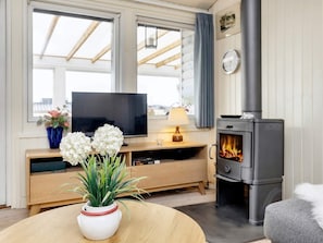 A cozy living room with a television, a fireplace, and a round table with a vase of flowers. - 5 Person Holiday Home in Karrebaeksminde (Karrebæksminde)