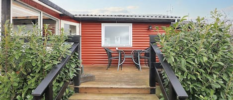 A wooden staircase leading to a red building with a window and a door.