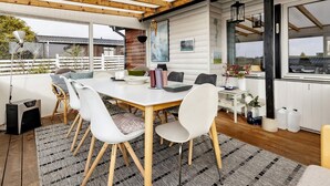 A covered outdoor dining area with a table and chairs, a lamp, and a view of the outside. - 5 Person Holiday Home in Karrebaeksminde (Karrebæksminde)