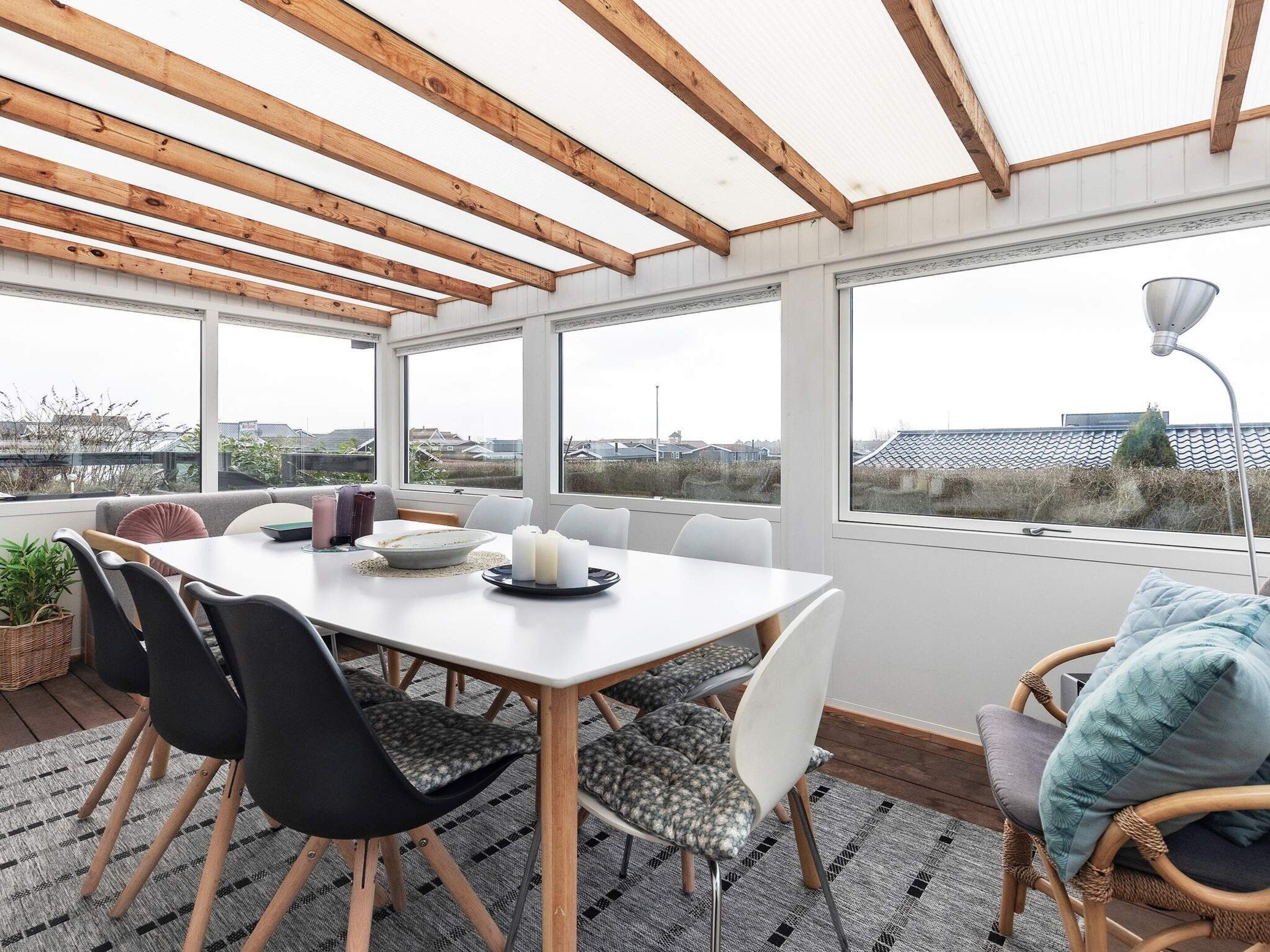 A dining area with a table, chairs, and a view through large windows.