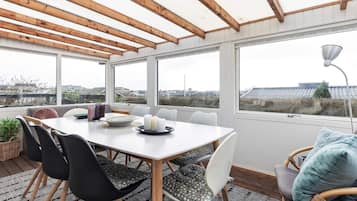 A dining area with a table, chairs, and a view through large windows.