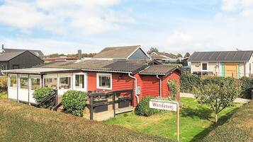 A red wooden house with a sign reading "Wondasvej" in a residential area with other houses.