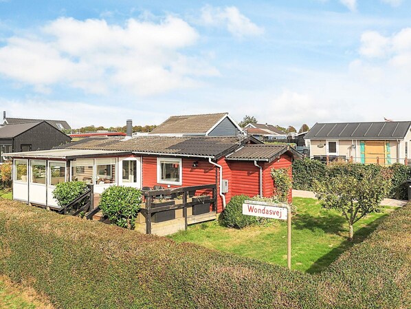 A red wooden house with a sign reading "Wondasvej" in a residential area with other houses. - 5 Person Holiday Home in Karrebaeksminde (Karrebæksminde)