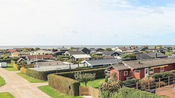 A residential area with houses, a gravel path, and a body of water in the background.