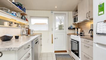 A compact kitchen with white cabinetry, a built-in microwave, and a small oven.
