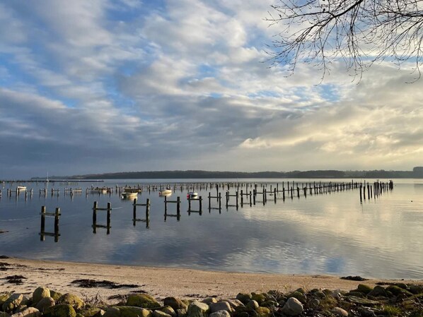 A calm lake with wooden docks extending into the water, surrounded by a rocky shoreline. - 6 Person Holiday Home in Haderslev (Haderslev)