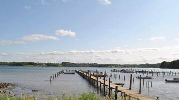 A calm lake with wooden docks extending into the water, surrounded by greenery and a clear sky.