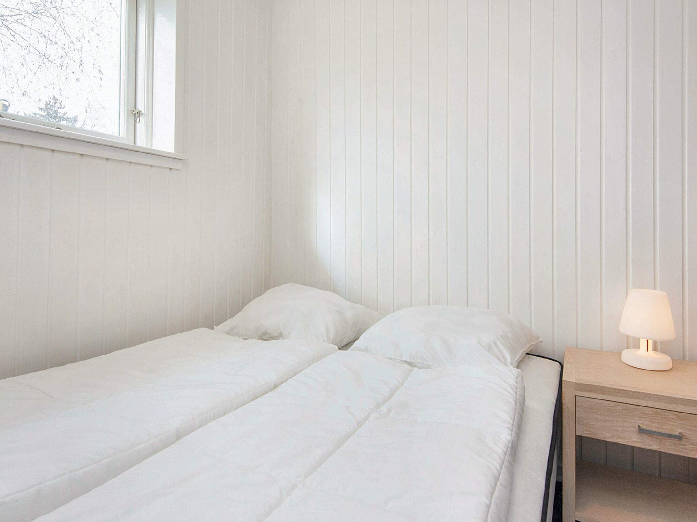 A single bed with white bedding in a room with vertical paneling on the walls.
