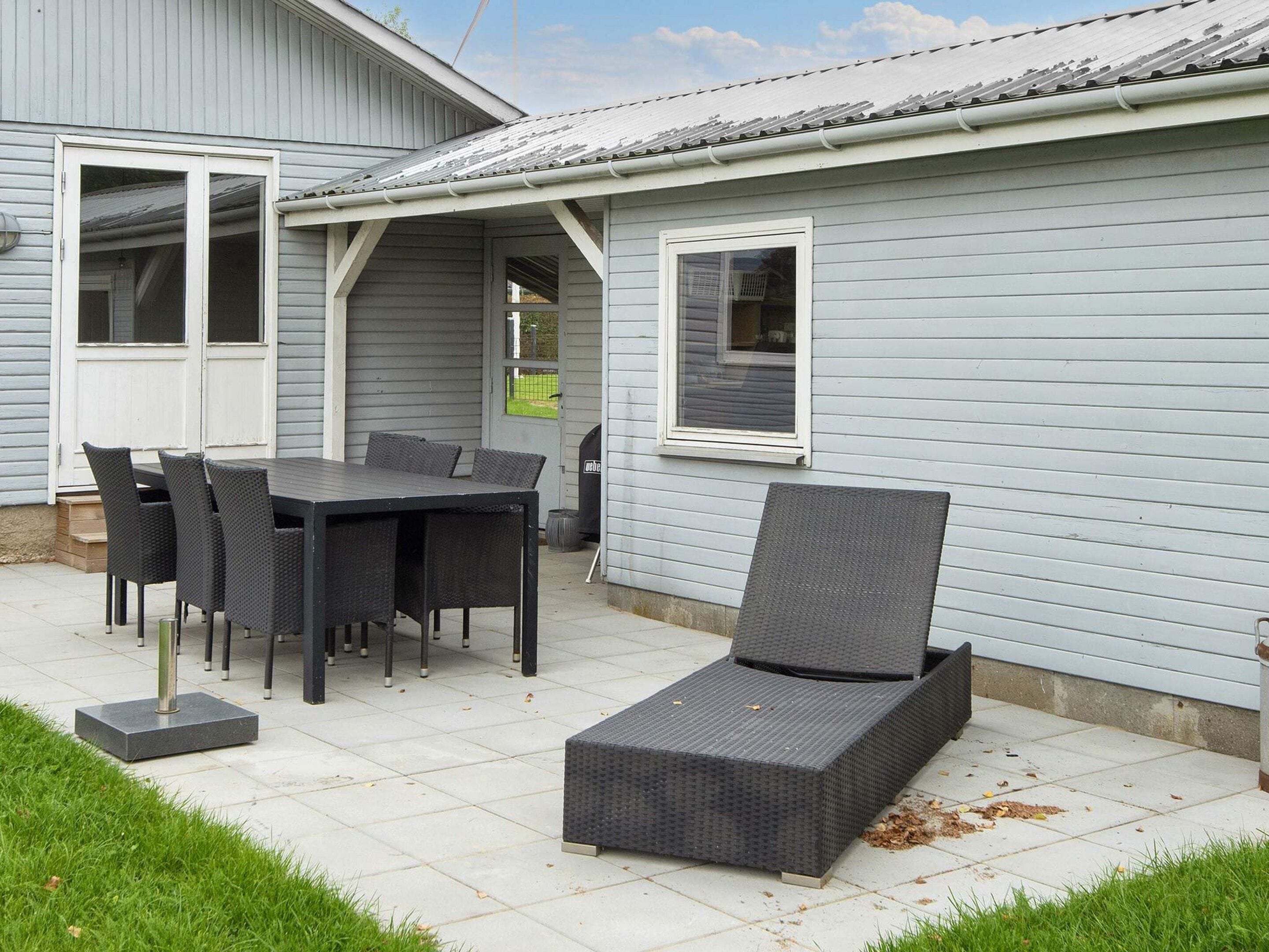 A patio area with a table and chairs, a covered seating area, and a small garden.