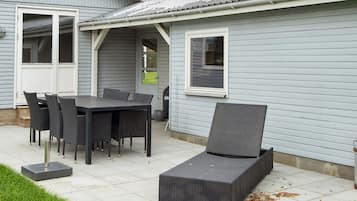 A patio area with a table and chairs, a covered seating area, and a small garden.