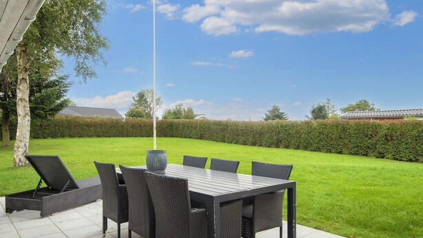 Un patio exterior con una mesa, sillas, un florero y un asta de bandera.