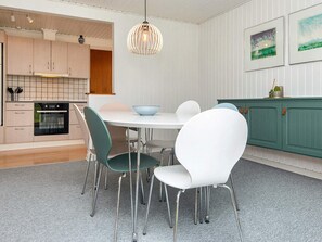 A modern kitchen with a dining area, featuring a round table, chairs, and a hanging light fixture. - 6 Person Holiday Home in Haderslev (Haderslev)