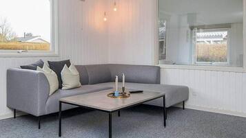 A modern living room with a grey sectional sofa, a small table, and a large window providing a view of the outside.