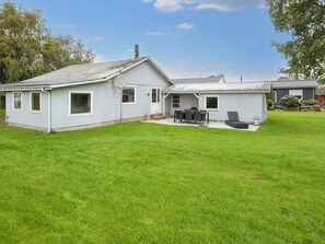 Une maison de plain-pied dotée d’un patio couvert, d’un petit garage attenant et d’une pelouse bien entretenue.