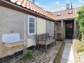 A rustic building with a tiled roof, a bench, a small table, and a door. - 4 Person Holiday Home in Nysted (Nysted)