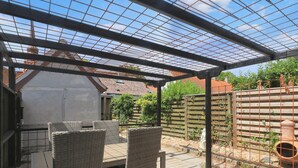 A covered patio area with wicker furniture and a pergola structure. - 4 Person Holiday Home in Nysted (Nysted)