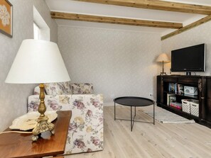 A living room with a sofa, a small round table, a lamp, a television, and a bookshelf. - 4 Person Holiday Home in Nysted (Nysted)