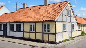 A traditional half-timbered house with a red-tiled roof, a chimney, and a street view. - 4 Person Holiday Home in Nysted (Nysted)