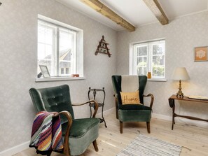 A room with two green armchairs, a small table with a lamp, and a window with a view of a house. - 4 Person Holiday Home in Nysted (Nysted)