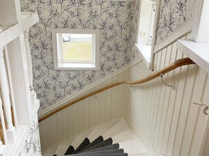 A staircase with white walls and a window at the top.