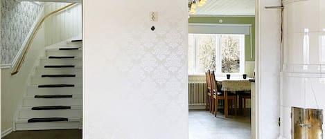 A staircase leading to a landing, a dining area with a table and chairs, and a white cylindrical object.