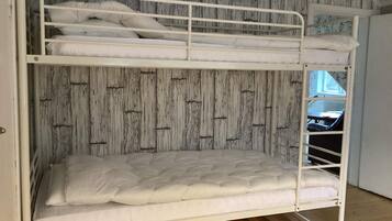 A bunk bed with a wooden wall and a window.