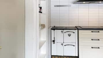 Una cocina con armarios blancos, una estufa y una campana extractora negra.