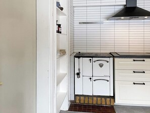 A kitchen with white cabinets, a stove, and a black range hood.