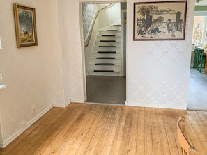 A hallway with a wooden floor, a staircase, and two framed pictures on the walls. - 8 Person Holiday Home in Anneby (Aneby)