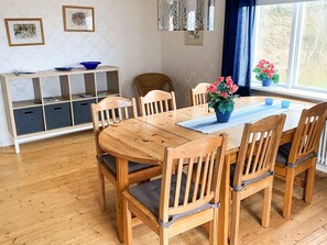 A dining area with a wooden table and chairs, a blue placemat, and a potted plant with pink flowers. - 8 Person Holiday Home in Anneby (Aneby)